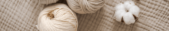 junikind Bio-Baumwolle und Wolle liegen auf Tuch aus natürlicher Bio-Baumwolle